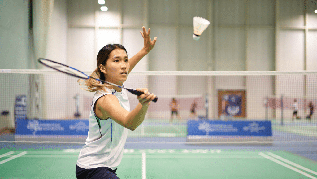 Règle du badminton - joueur en action lors d'un smash sur un terrain de badminton en salle